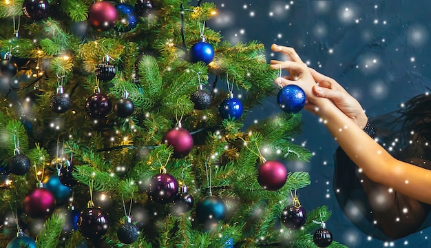 A family decorates a Christmas tree at night. Selective focus. Holiday.