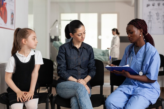 Family discussing medical treatment with african american nurse in hospital