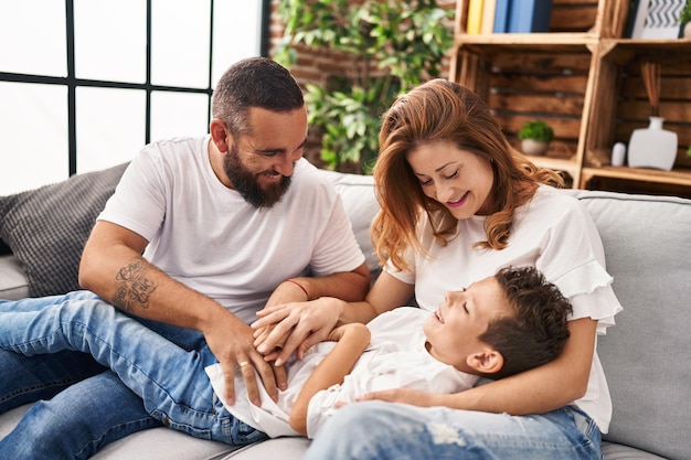 Family doing tickle to son sitting on sofa at home