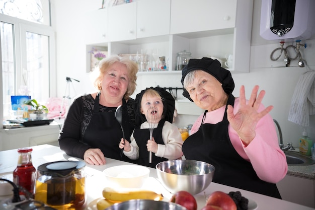 Family eating pancakes and drinking tea in the kitchen posing for the camera and waving hands