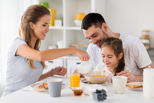 family eating and people concept happy mother father and daughter having breakfast at home