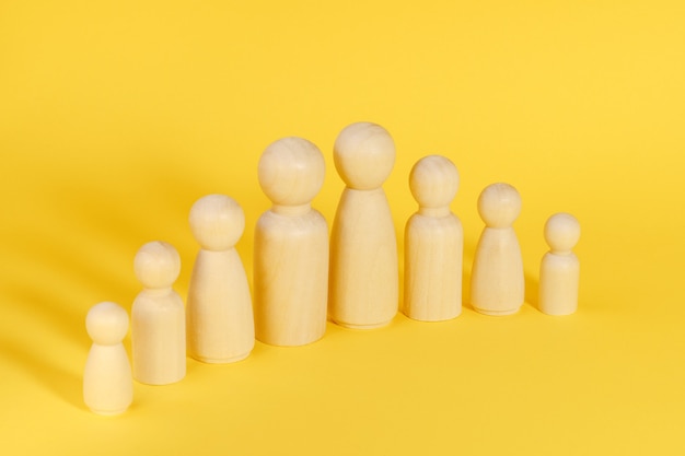 Family of eight members made from wooden figurines on yellow background