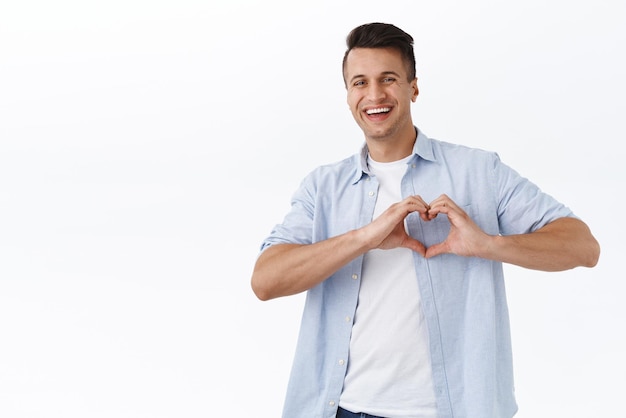 Family feelings and holidays concept Cheerful adult handsome man express sympathy or like sharing his happy emotions with world happy easter show hear sign and smiling white background