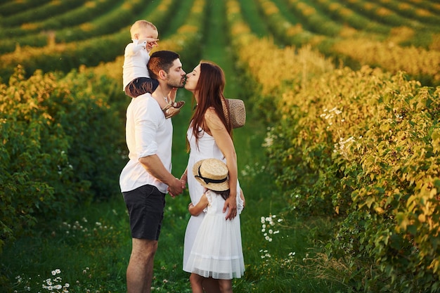 Family of four people spending free time on the field at sunny day time of summer