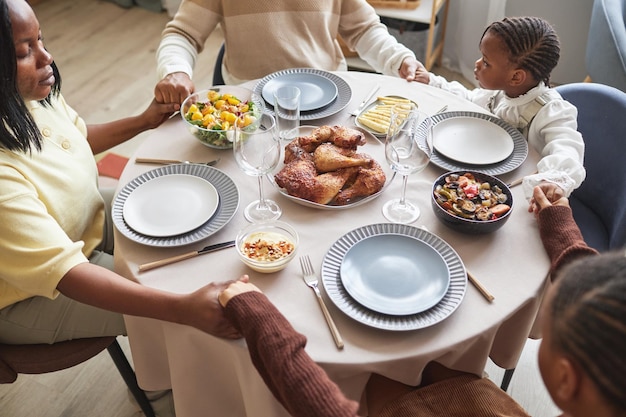 Family of four praying before dinner