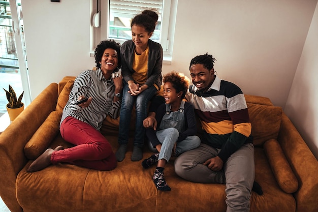 Family of four watching tv from the sofa at home