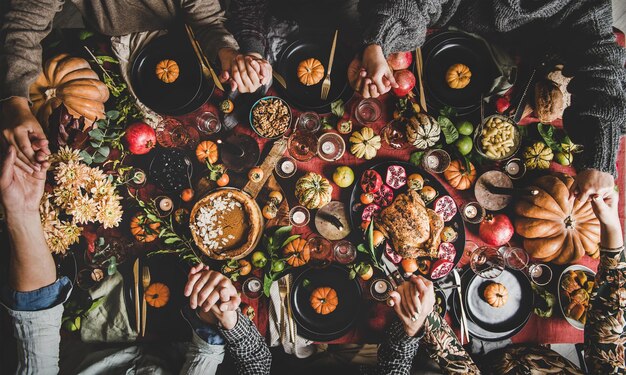 Photo family or friends praying holding hands at thanksgiving celebration table