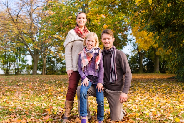 Family in front of colorful trees in autumn or fall