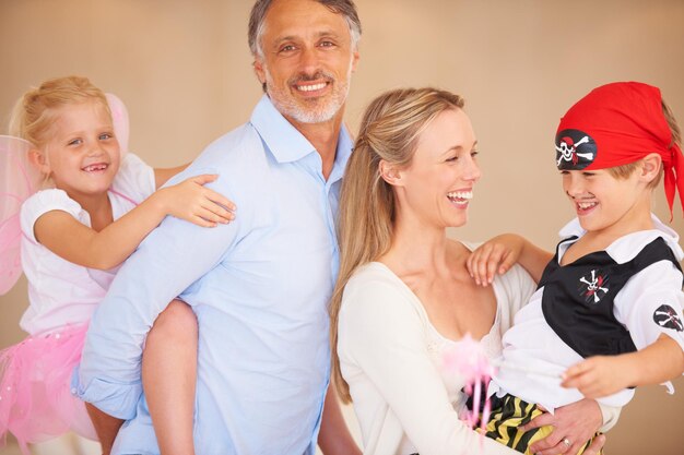 Photo family full of fun a family portrait of a father piggybacking his daughter and bother carrying her son on halloween