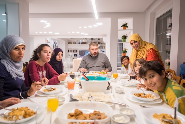 Family gathering eating meal around kitchen table