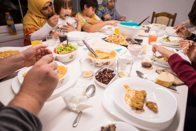 Family gathering eating meal around kitchen table