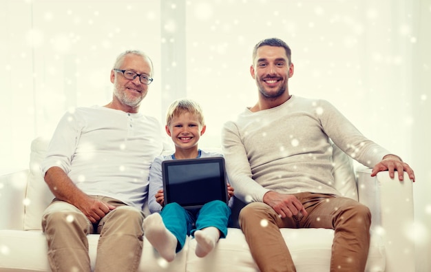 family, generation, technology and people concept - smiling father, son and grandfather sitting on couch with tablet pc computer at home