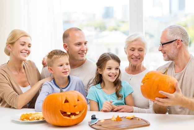 family, happiness, generation, holidays and people concept - happy family making halloween pumpkins at home