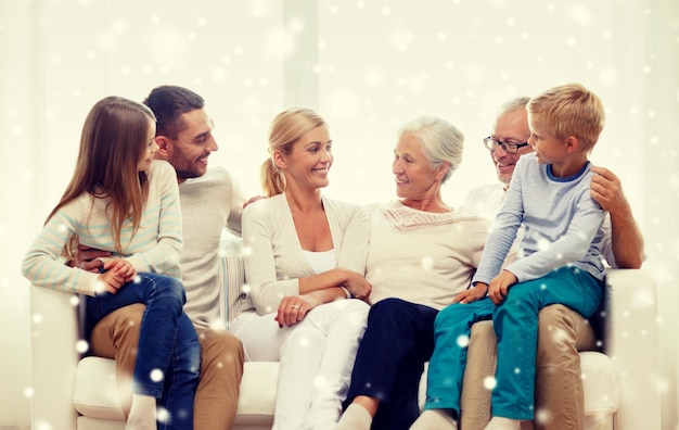 family, happiness, generation and people concept - happy family sitting on couch at home