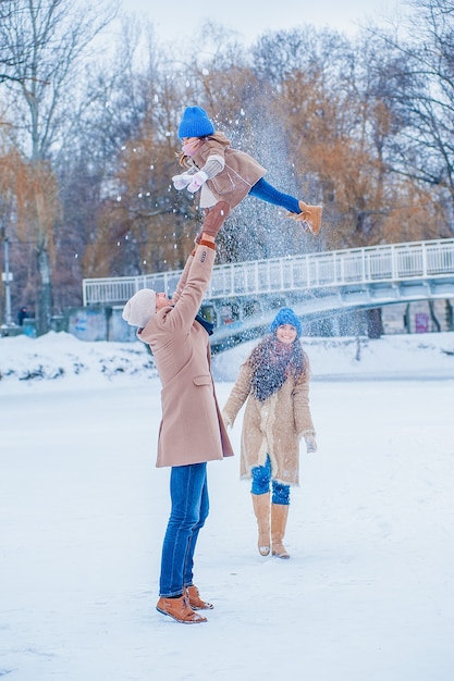 Family have fun on a frozen lake in the park against the background of the bridge