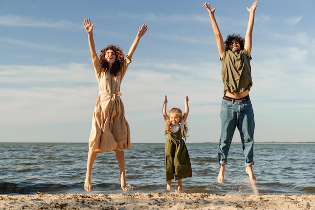 Family having fun and jumping on the beach spending vacation on holiday