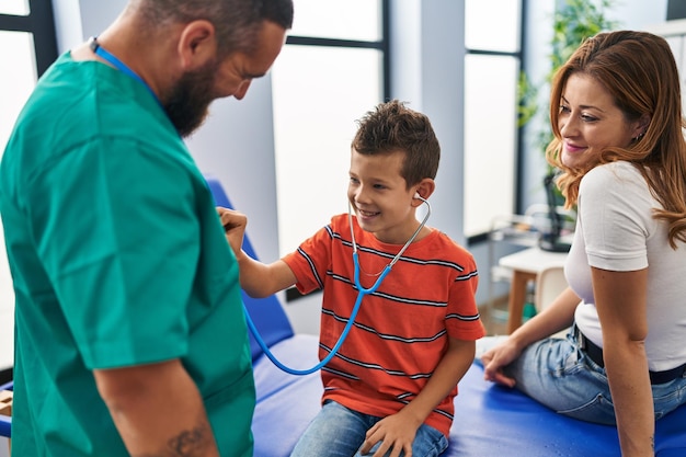 Family having medical consultation child auscultating doctor heart at clinic