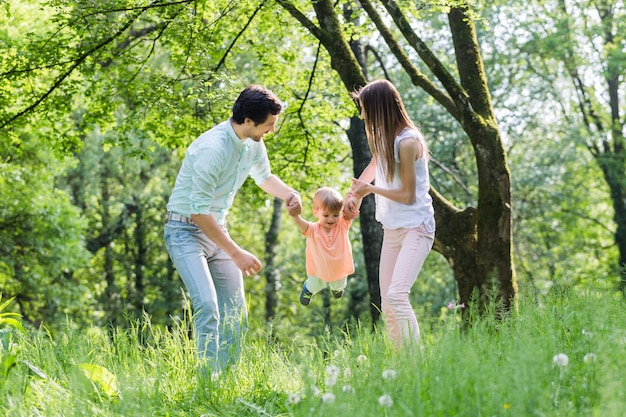 Family having walk together in summer holding hands and letting the little boy fly