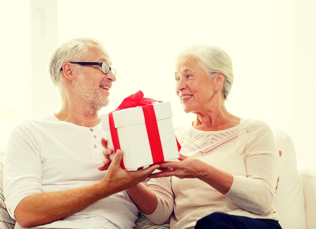 family, holidays, christmas, age and people concept - happy senior couple with gift box at home