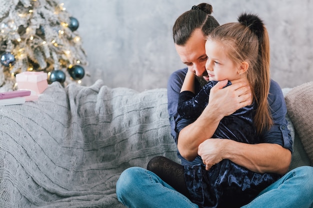 Family home Christmas celebration. Happy father hugging his cute little daughter, smiling. Copy space.