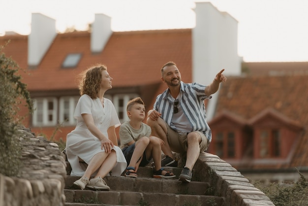 A family is relaxing on the stairs between roofs in an old European town