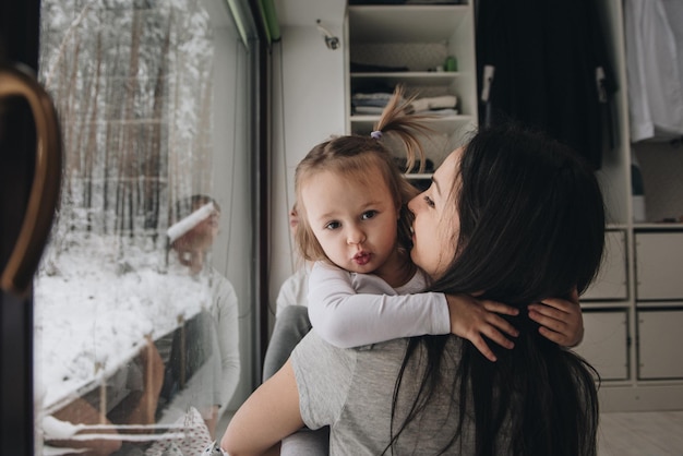 The family is sitting at the window and looking at the winter forest. Good New Year spirit. Morning in pajamas.