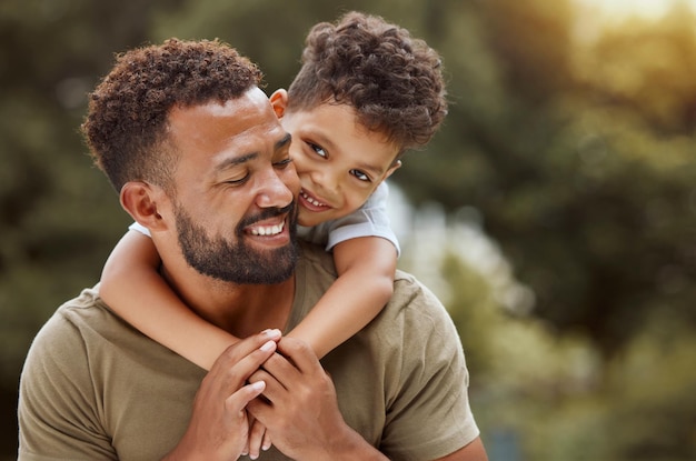 Family love and father with son at a park relax and embrace while enjoying quality time bonding and fun in nature Black family kids and parent hug smile and enjoy free time and a walk in forest