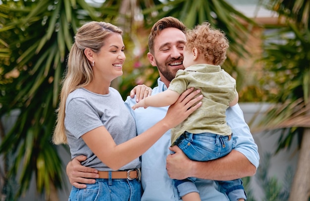 Family love and parents with child in garden with smile happy and hug together in summer Excited relax and loving mother and father on outdoor holiday with a kid in a park nature or backyard