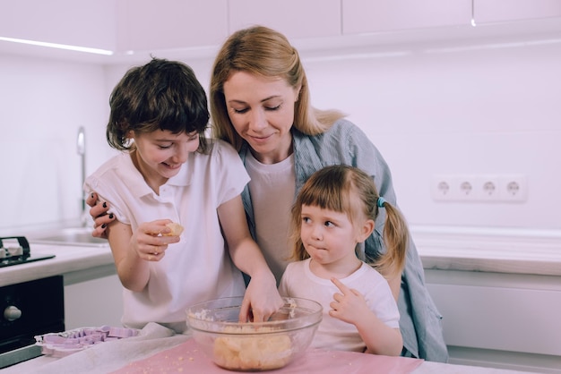 Family makes cookies at home Mom teaches her daughters to knead dough in the kitchen