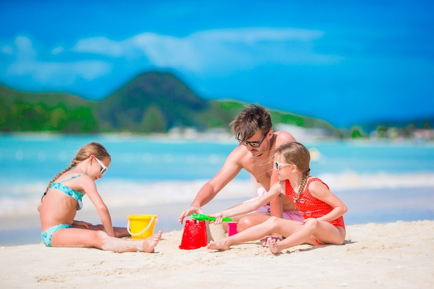 Family making sand castle at tropical white beach. 