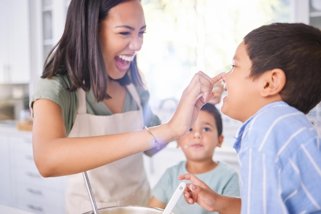 Family mom and cooking in kitchen with children having fun and bonding in home Happy smile and mother playing with boys care and spending quality time together helping and learning how to cook