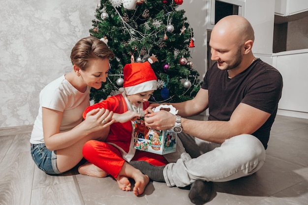 Family mom dad and son in a Santa costume open a Christmas gift