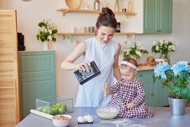 Family mother and baby daughter in morning have breakfast in kitchen. 