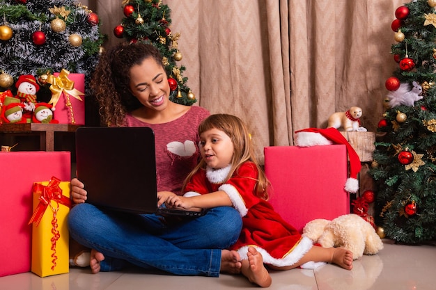 Family mother and child girl use laptop at home on Christmas vacation.