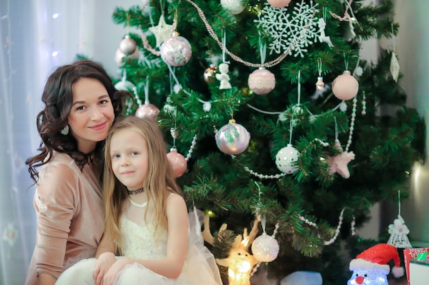 Family og mom and little daughter near the Christmas tree on xmas eve