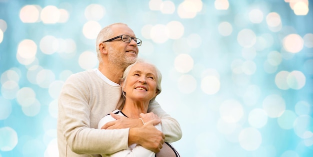 family, old age, love and people concept - happy senior couple over blue holidays lights background