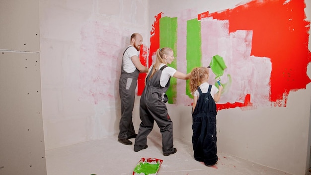 Family painting walls in the new apartment in green and red colors