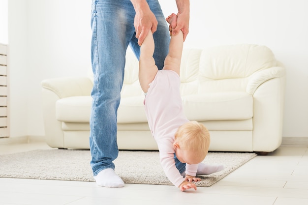 family, parenthood and fatherhood concept - happy father playing with little baby girl at home