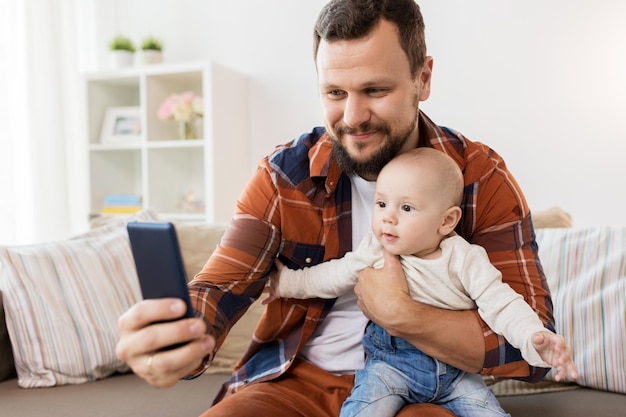 family parenthood and people concept happy father with little baby boy taking selfie at home