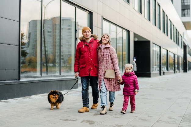 Family,parenthood and people concept-happy mother, father and little girl walking in autumn city and having fun.