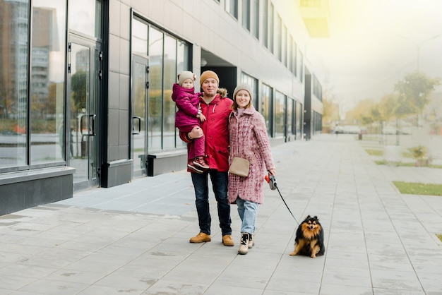 Family,parenthood and people concept-happy mother, father and little girl walking in autumn city and having fun.