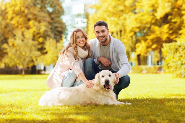 family, pet, domestic animal, season and people concept - happy couple with labrador retriever dog walking in autumn city park