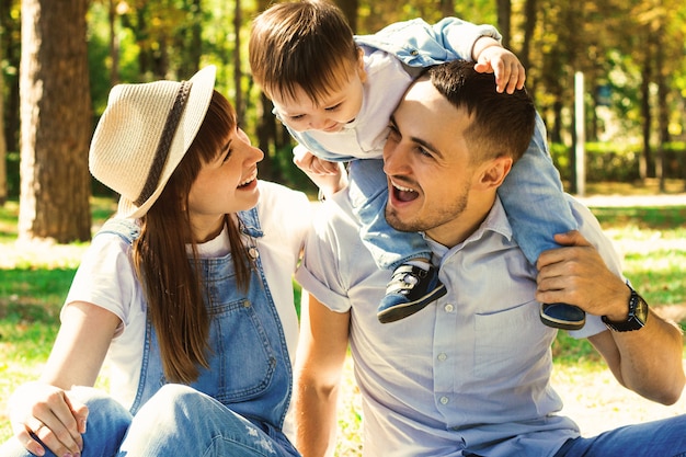 Family at a picnic. Happy beautiful family having fun in park. Child sits on mans shoulders.