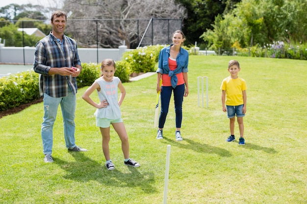 Family playing cricket in park