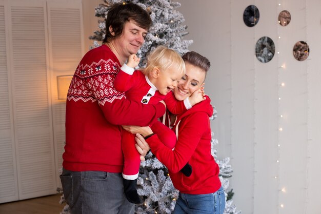 Family playing at home near Christmas tree. Christmas tree on the background.