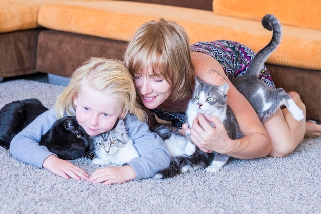 Family portrait with caucasian mother blonde beautiful middle age woman and young white skin son and two lovely adorable cats group hug with persons and animals best friends forever together concept