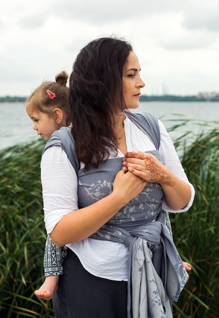 Family portrait with mother and daughter wrapped back at grey sling outdoors