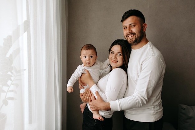 A family poses in front of a window with a white curtain that says'i'm a baby '