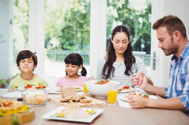 Family praying at dining table 