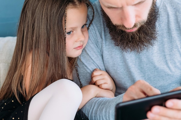 Family problems lack of communication and digital device addiction child daughter hugging her daddy father looking at mobile phone bad parenting habits and irresponsible fatherhood